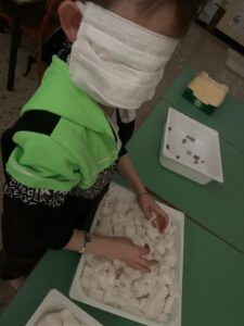 alunno bendato tocca oggetti in una vaschetta del percorso sensoriale